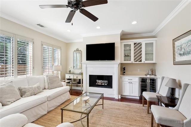 living room with ornamental molding, ceiling fan, hardwood / wood-style floors, wine cooler, and bar