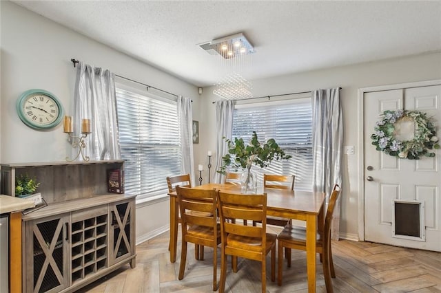 dining area featuring light parquet floors and a textured ceiling