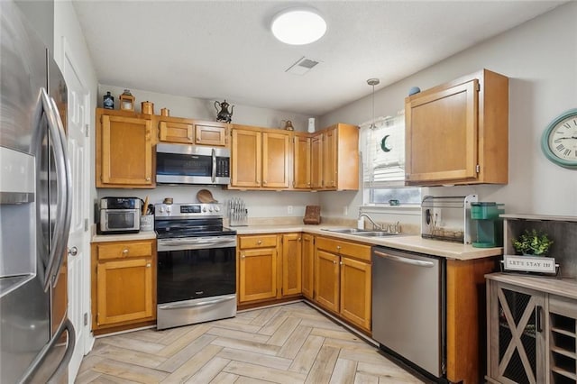 kitchen featuring hanging light fixtures, light parquet floors, stainless steel appliances, and sink