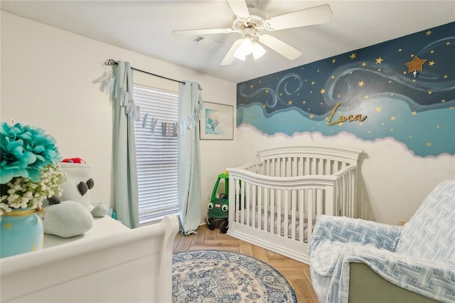 bedroom featuring a crib, ceiling fan, and parquet flooring