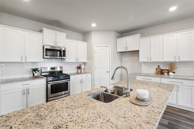 kitchen featuring sink, white cabinetry, backsplash, stainless steel appliances, and light stone countertops