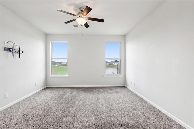 empty room with carpet floors, a wealth of natural light, and ceiling fan