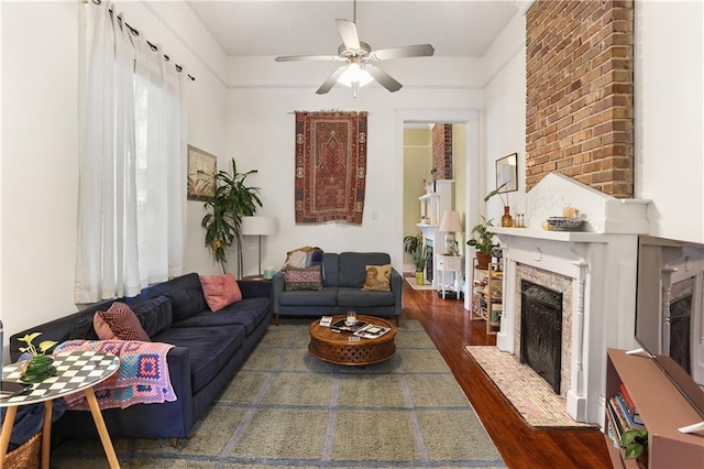 living room featuring ceiling fan, dark hardwood / wood-style flooring, and a brick fireplace