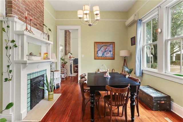 dining area featuring a wall mounted AC, a fireplace, an inviting chandelier, and hardwood / wood-style flooring