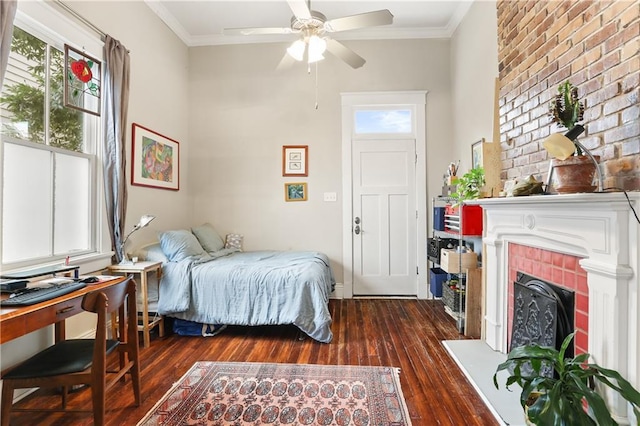 bedroom featuring a brick fireplace, ceiling fan, dark wood-type flooring, and crown molding