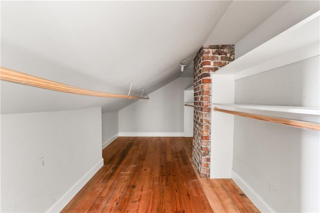 walk in closet with dark wood-type flooring and vaulted ceiling