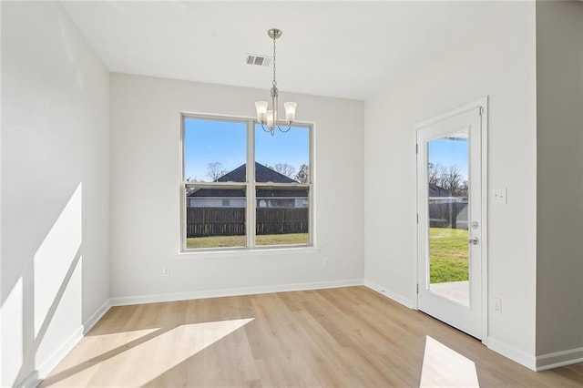 unfurnished dining area featuring light wood-type flooring and a chandelier