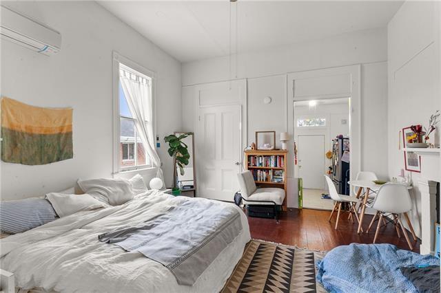 bedroom featuring hardwood / wood-style flooring and a wall unit AC