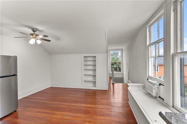 additional living space with built in shelves, baseboards, ceiling fan, cooling unit, and wood finished floors