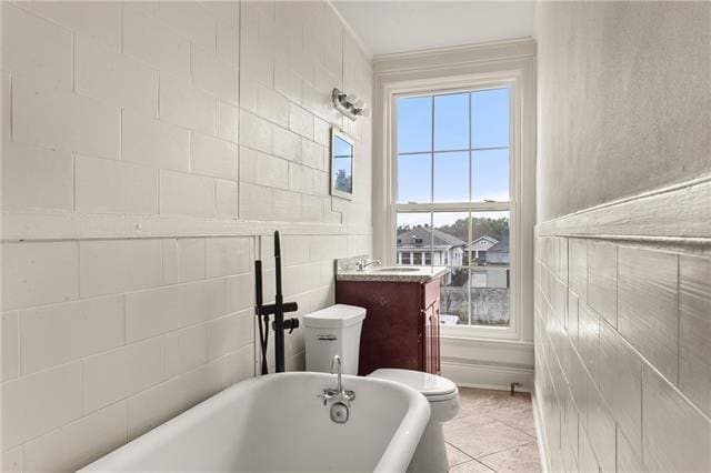 full bath with ornamental molding, toilet, a soaking tub, vanity, and tile patterned floors