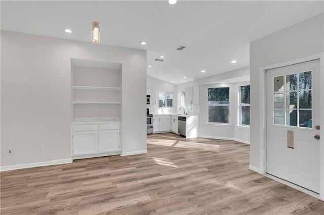 interior space featuring sink, built in features, lofted ceiling, and light hardwood / wood-style flooring