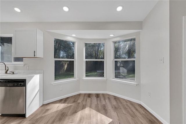 kitchen with dishwasher, white cabinets, sink, light hardwood / wood-style floors, and light stone counters