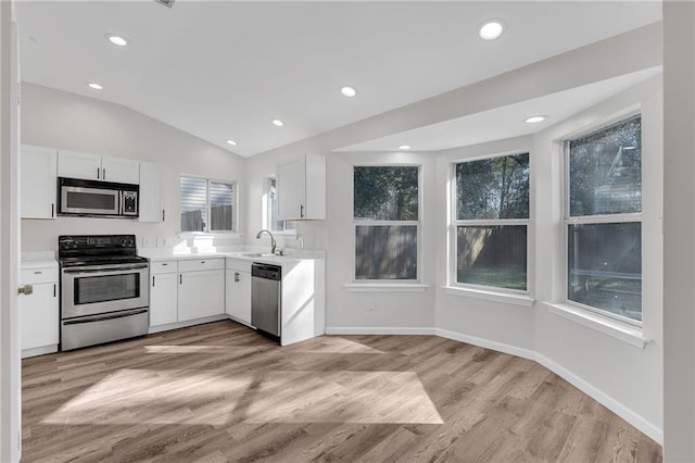 kitchen featuring white cabinets, light hardwood / wood-style floors, vaulted ceiling, and appliances with stainless steel finishes