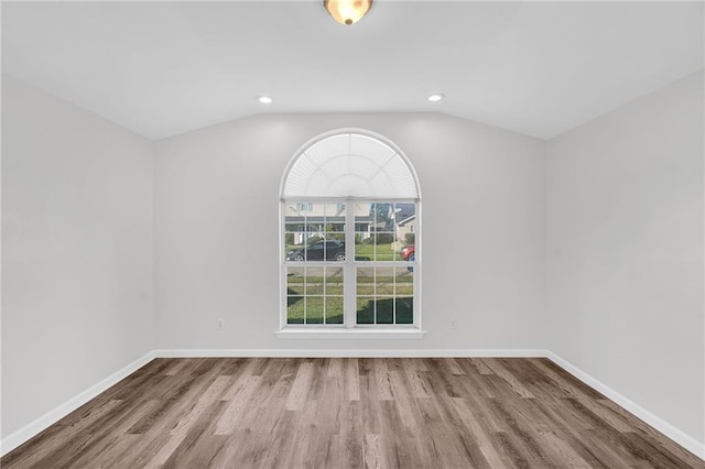 unfurnished room featuring wood-type flooring and lofted ceiling