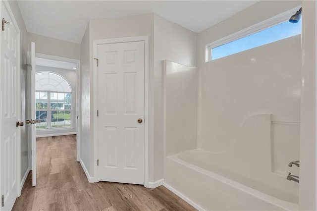 bathroom with hardwood / wood-style floors and washtub / shower combination