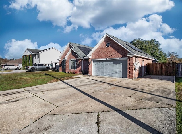 view of front facade with a front lawn, a garage, and solar panels