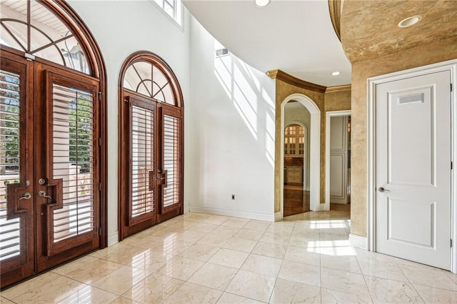 entrance foyer featuring french doors, ornamental molding, and a healthy amount of sunlight