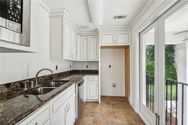 kitchen featuring sink, white cabinets, a wealth of natural light, dark stone counters, and appliances with stainless steel finishes