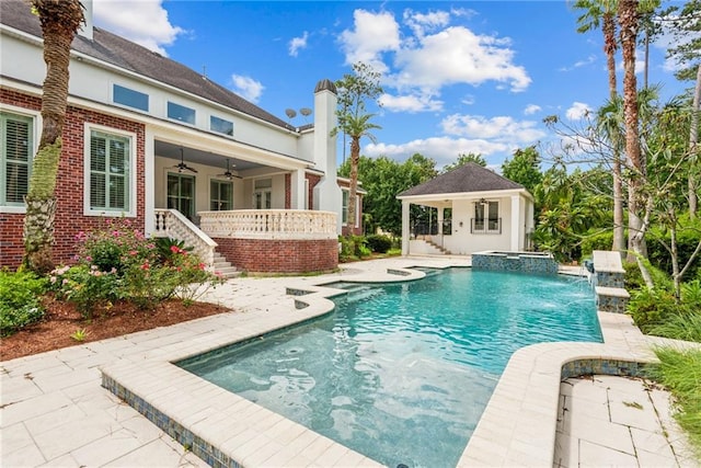 view of swimming pool featuring a patio area, an outdoor structure, ceiling fan, pool water feature, and an in ground hot tub