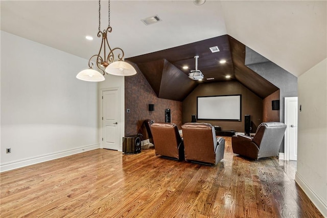 home theater room with hardwood / wood-style floors and vaulted ceiling