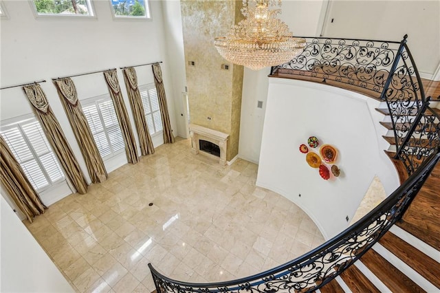 foyer with a high ceiling, a tiled fireplace, and a notable chandelier