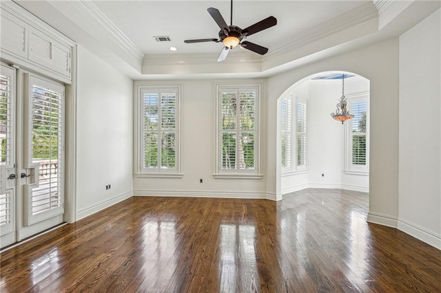 unfurnished room featuring ornamental molding, dark hardwood / wood-style flooring, ceiling fan with notable chandelier, and a tray ceiling