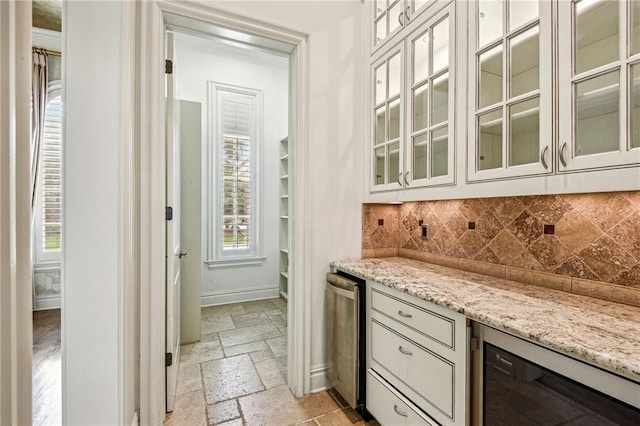 bar featuring refrigerator, beverage cooler, backsplash, and light stone counters