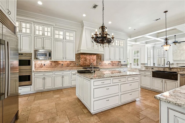 kitchen featuring appliances with stainless steel finishes, pendant lighting, an island with sink, and coffered ceiling