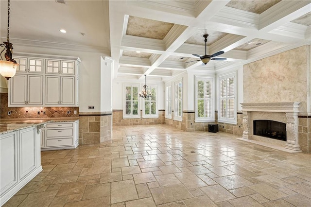 unfurnished living room with coffered ceiling, a premium fireplace, beamed ceiling, ornamental molding, and ceiling fan with notable chandelier