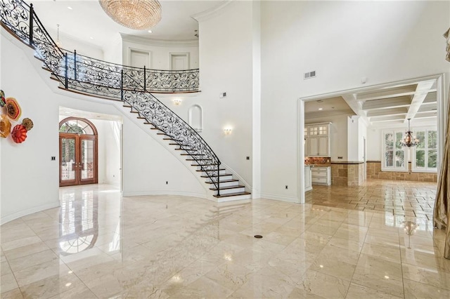 foyer with a towering ceiling, french doors, coffered ceiling, crown molding, and beam ceiling