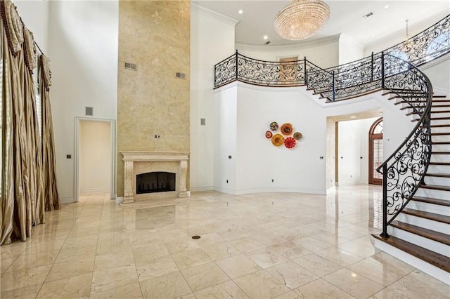 unfurnished living room featuring ornamental molding, a towering ceiling, and a high end fireplace