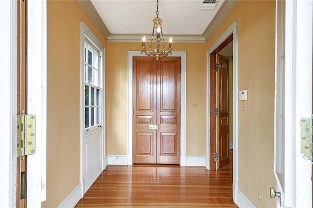 hall with crown molding, hardwood / wood-style floors, and an inviting chandelier