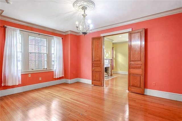 unfurnished room with light hardwood / wood-style flooring, an inviting chandelier, and ornamental molding