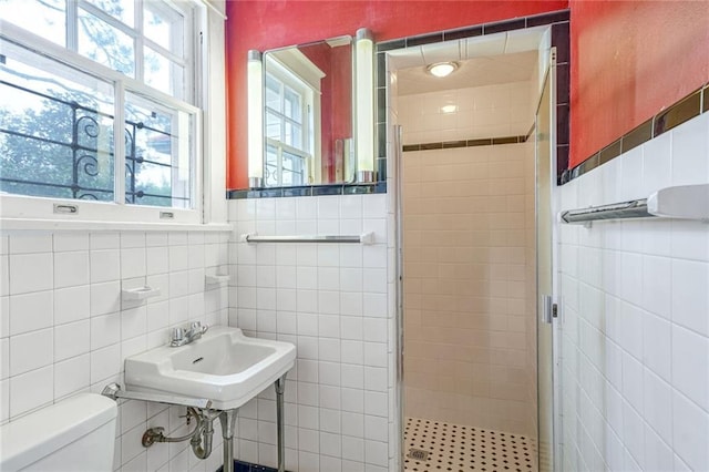 bathroom featuring toilet, sink, tile walls, and walk in shower