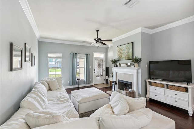 living room featuring dark hardwood / wood-style floors, ceiling fan, ornamental molding, and a tile fireplace