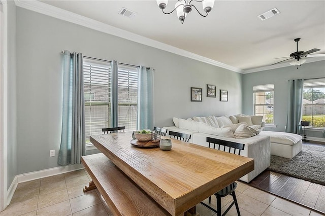 tiled dining area with ceiling fan with notable chandelier, a wealth of natural light, and ornamental molding