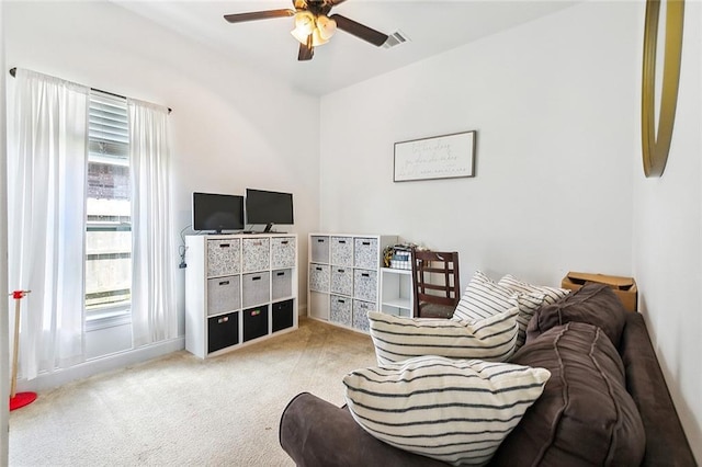 living area featuring light colored carpet, ceiling fan, and a healthy amount of sunlight