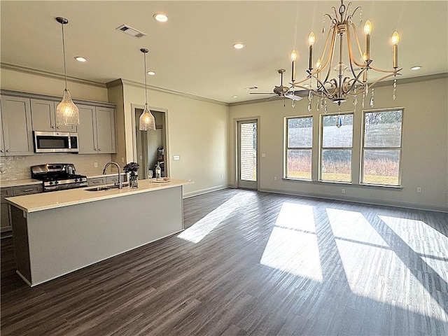 kitchen with dark hardwood / wood-style flooring, gray cabinetry, stainless steel appliances, pendant lighting, and an island with sink