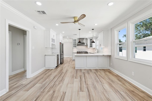 kitchen with wall chimney exhaust hood, white cabinetry, high end refrigerator, decorative light fixtures, and kitchen peninsula