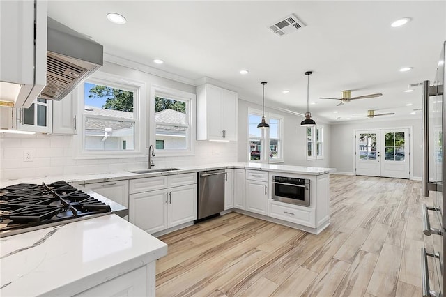 kitchen featuring pendant lighting, sink, stainless steel appliances, white cabinets, and kitchen peninsula