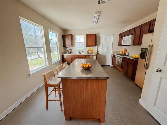 kitchen featuring a kitchen bar, dark hardwood / wood-style floors, a center island, and fridge with ice dispenser