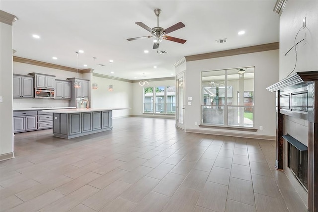 kitchen with ornamental molding, ceiling fan, pendant lighting, a center island, and gray cabinets