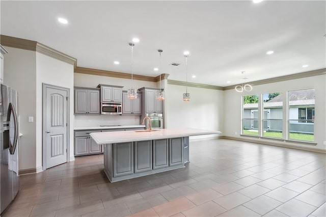 kitchen featuring gray cabinetry, sink, stainless steel appliances, an island with sink, and pendant lighting