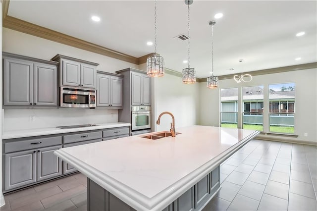 kitchen with sink, an island with sink, decorative light fixtures, gray cabinets, and appliances with stainless steel finishes