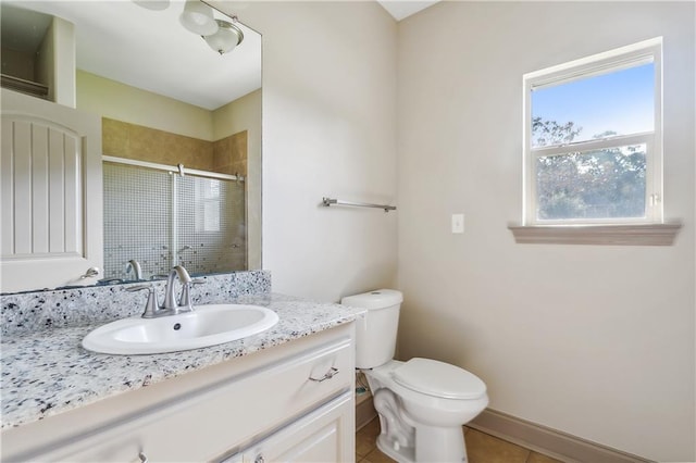 bathroom featuring tile patterned floors, vanity, toilet, and a shower with door