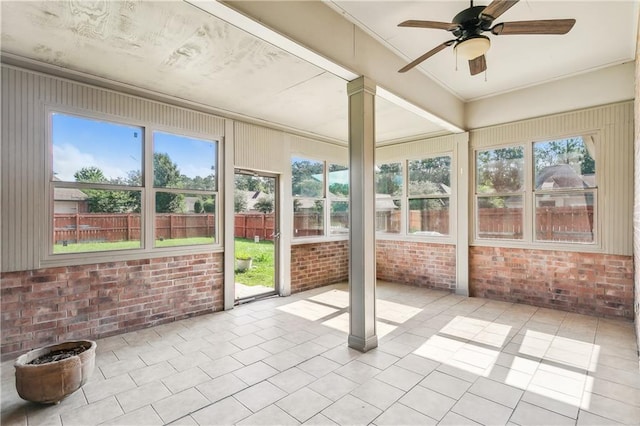 unfurnished sunroom featuring ceiling fan and decorative columns