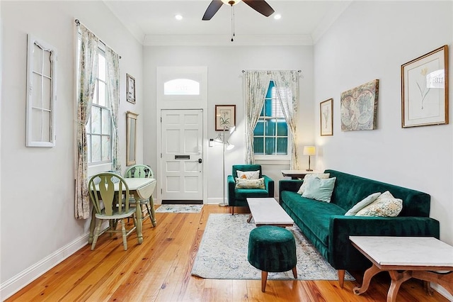 living area with ornamental molding, ceiling fan, and light wood-type flooring