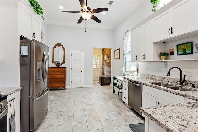 kitchen with sink, crown molding, appliances with stainless steel finishes, light stone countertops, and white cabinets