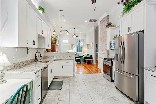 kitchen featuring white cabinetry, stainless steel appliances, decorative light fixtures, and sink