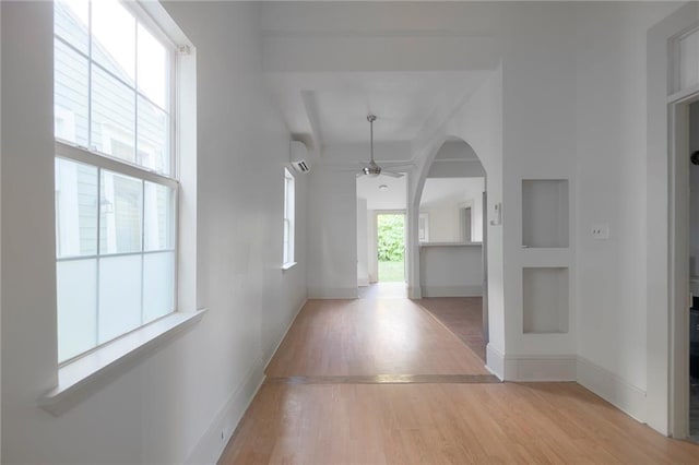 hallway featuring light hardwood / wood-style floors, a wall unit AC, and plenty of natural light